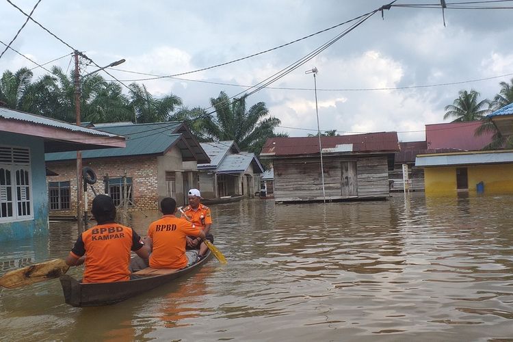 Petugas BPBD Kampar mengecek ketinggian banjir di Desa Buluh Cina, Kecamatan Siak Hulu, Kabupaten Kampar, Riau, Senin (23/12/2019). Petugas juga meminta warga mengungsi apabila ketinggian banjir terus bertambah.