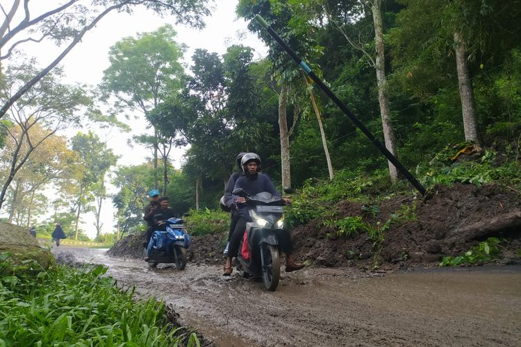 Pemudik melintasi jalan Raya Cipatat-Saguling, Bandung Barat yang tertimbun material longsor, Kamis (20/4/2023).