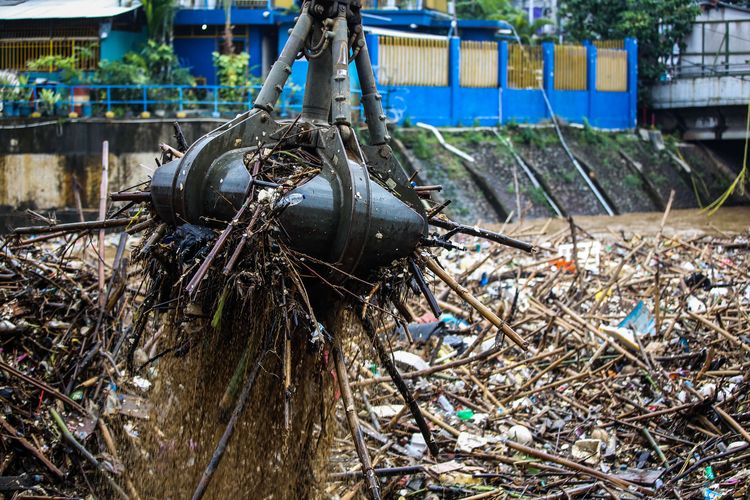 Petugas kebersihan DKI Jakarta mengangkut sampah yang terbawa arus menggunakan alat berat di Pintu Air Manggarai, Jakarta Pusat, Selasa (22/9/2020). Kenaikan muka air di Pintu Air Manggarai diakibatkan oleh hujan yang mengguyur kota Bogor dan Jakarta mulai Senin malam (21/9/2020) selama beberapa jam.