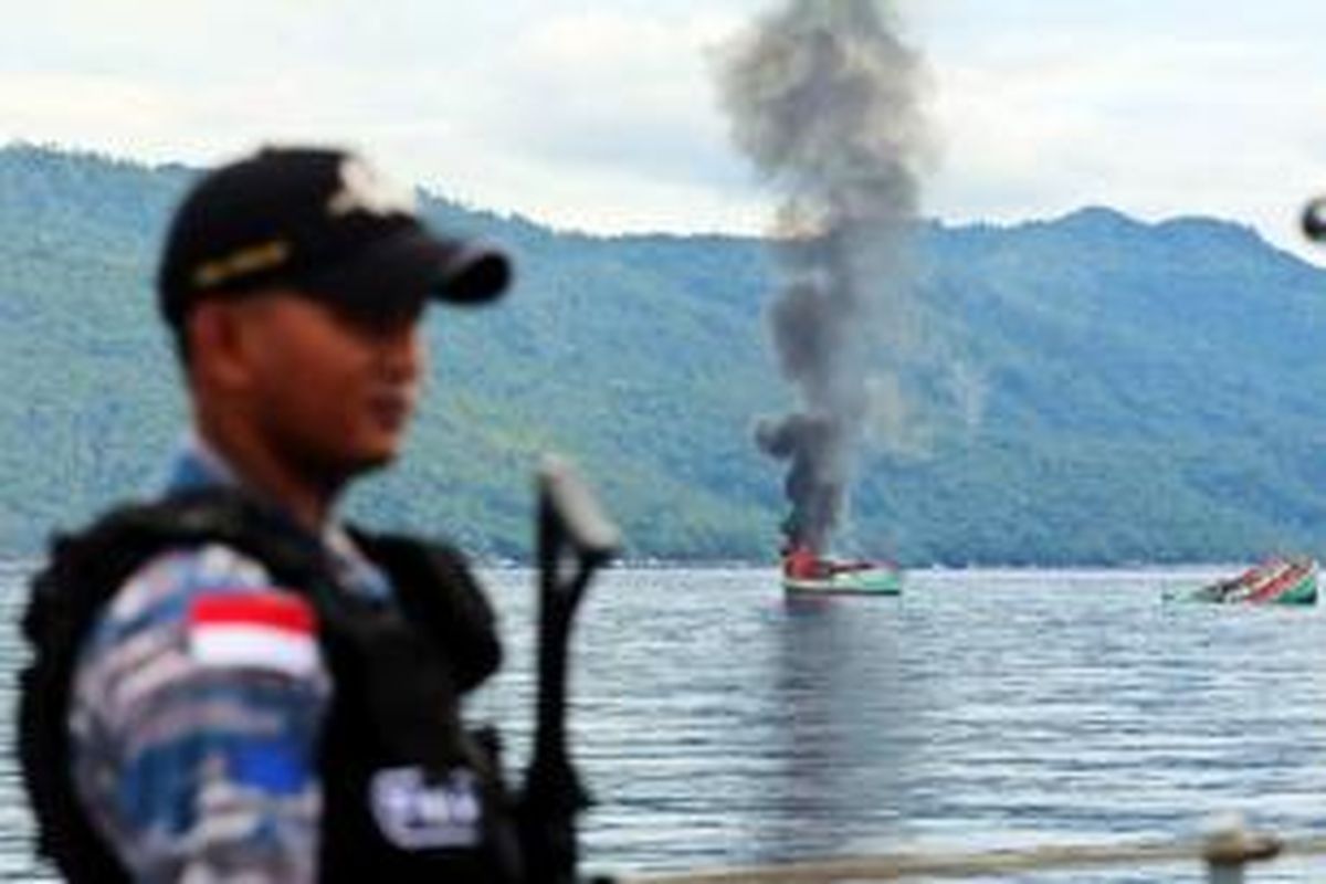 Anggota TNI AL memantau penenggelaman kapal milik nelayan asing di Perairan Anambas, Kepulauan Riau, Jumat (5/12/2014). Sebanyak tiga kapal Vietnam yang ditangkap TNI AL ditenggelamkan sebagai sikap tegas pemerintah Indonesia terhadap aksi pencurian ikan yang merugikan negara hingga Rp 300 triliun per tahun.