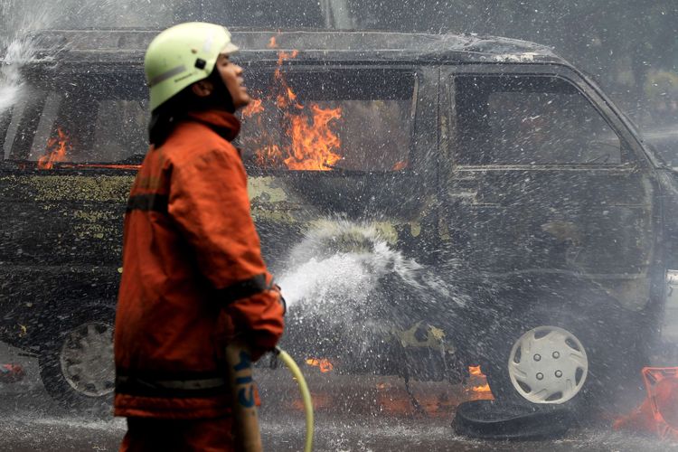 Petugas berusaha memadamkan mobil Daihatsu Zebra B2791AJ yang terbakar di Jalan Trunojoyo, samping Mabes Polri, Kebayoran Baru, Jakarta, Rabu (4/2/2015). Mobil itu membawa lima tangki berisi ratusan liter bahan bakar minyak.  KOMPAS IMAGES/KRISTIANTO PURNOMO