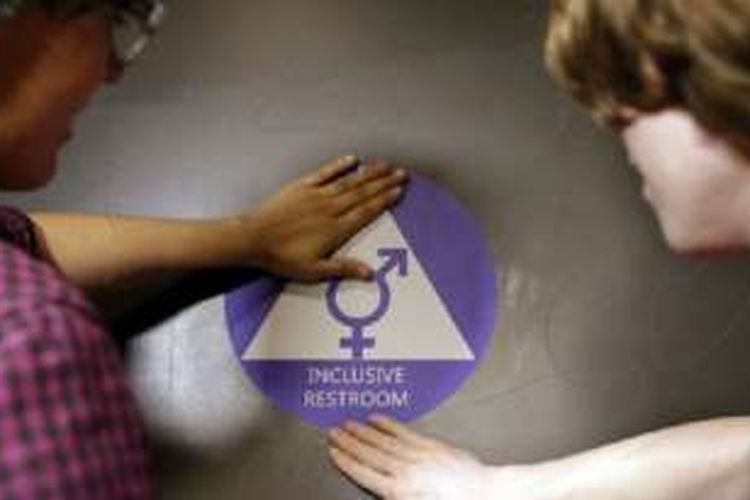 Dua murid di SMU Nathan Hale di Seattle, AS,  menempelkan stiker di pintu dalam upacara peresmian kamar mandi gender netral (17/5/2016). 
