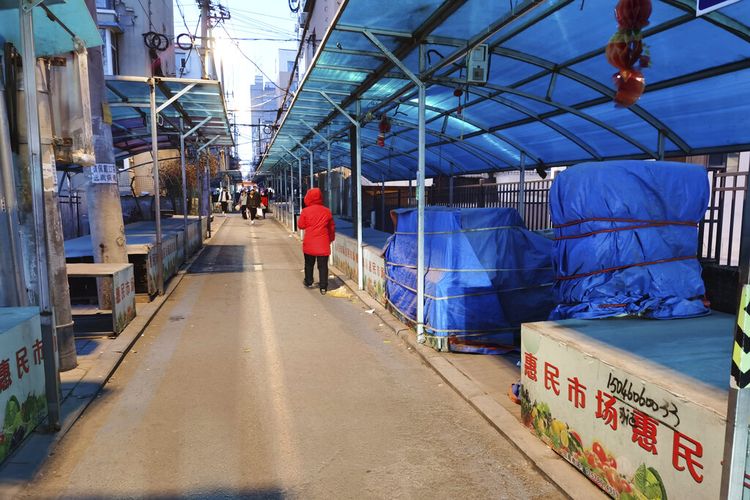 Orang-orang berjalan melalui pasar tertutup di Changchun di Provinsi Jilin, China timur laut, Jumat, 11 Maret 2022. 