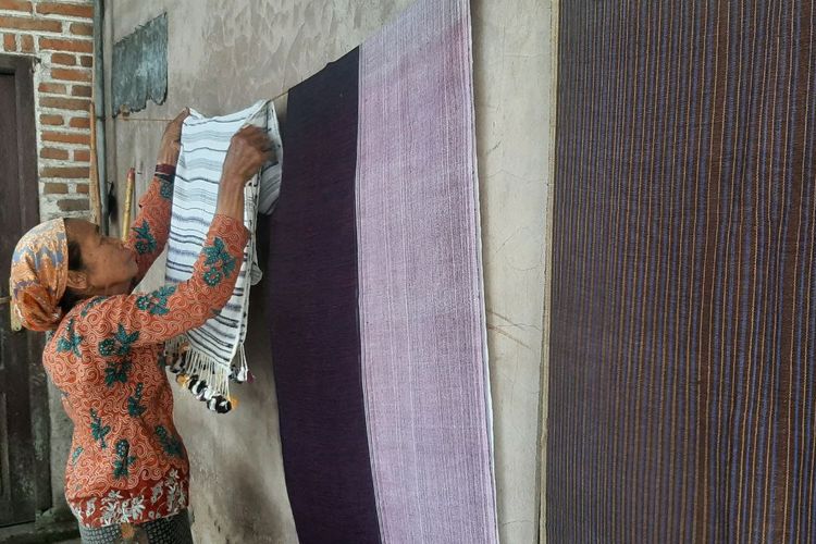 Perajin terakhir tenun khas Osing, Siami (73), menunjukkan hasil tenun tradisionalnya, di rumahnya, di Desa Jambesari, Kecamatan Giri, Kabupaten Banyuwangi, Jawa Timur, Senin (13/6/2022). Dari kanan, kain tenun khas Osing bermotif Gedog, Kuwung, dan Solok.