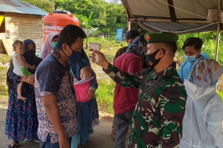 Petugas TNI memeriksa suhu tubuh seorang warga dari luar yang masuk ke arah Kota Bagansiapiapi, Rokan Hilir, Senin (13/7/2020). Pemeriksaan dilakukan di posko bagi setiap orang dari luar yang masuk ke wilayah Rohil, sebagai upaya mempertahankan status zona hijau.
