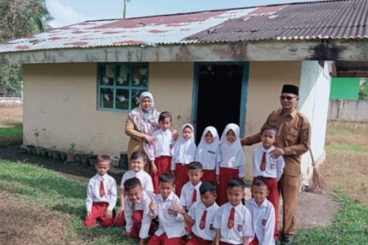 Kepala SDN 002 Tanjung, Kecamatan Koto Kampar Hulu, Kabupaten Kampar, Riau, Apriwardi (kanan) dan seorang guru foto bersama dengan murid yang belajar di ruang bekas WC, Selasa (11/6/2024).