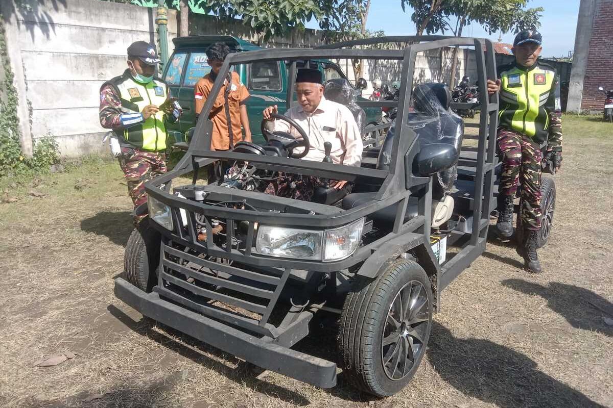 Ketua PCNU Kabupaten Jombang KH. Fahmi Amrullah Hadziq, saat mencoba mengendarai mobil listrik yang dirakit oleh anak-anak SMK NU Unggulan Mojoagung, Kabupaten Jombang, Jawa Timur, Kamis (19/12/2024).