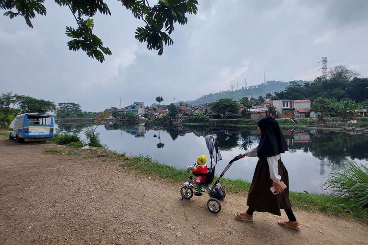 Warga beraktivitas di sekitar Situ Ciburuy, Kabupaten Bandung Barat yang berubah warna menjadi hitam pekat dan bau tak sedap setelah tercemar limbah, Kamis (14/7/2022).