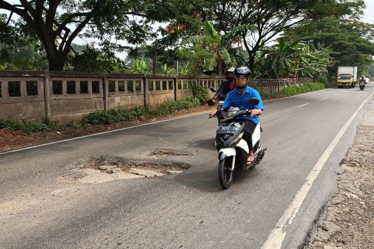 Pengendara sepeda motor saat menghindari jalan rusak berlubang di Akses Kalimalang, Cibitung, Kabupaten Bekasi menuju arah Karawang, Senin (22/5/2023). Lubang berdiameter kurang lebih 70 centimeter dengan kedalaman sekitar 15 centimeter itu membuat para pengendara kesulitan.