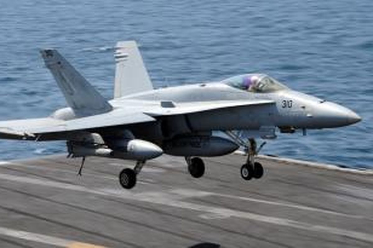 Dalam foto yang dirilis Angkatan Laut AS ini terlihat sebuah jet tempur F/A-18C Hornet bersiap untuk mendarat di atas landasan di kapal induk USS George HW Bush, pada Juli lalu di perairan Teluk Persia. Pesawat tempur jenis inilah yang digunakan dalam serangan udara yang mengincar posisi pasukan Negara Islam Irak dan Suriah (ISIS) yang berada di luar kot Arbil, wilayah otonomi Kurdi, Irak.