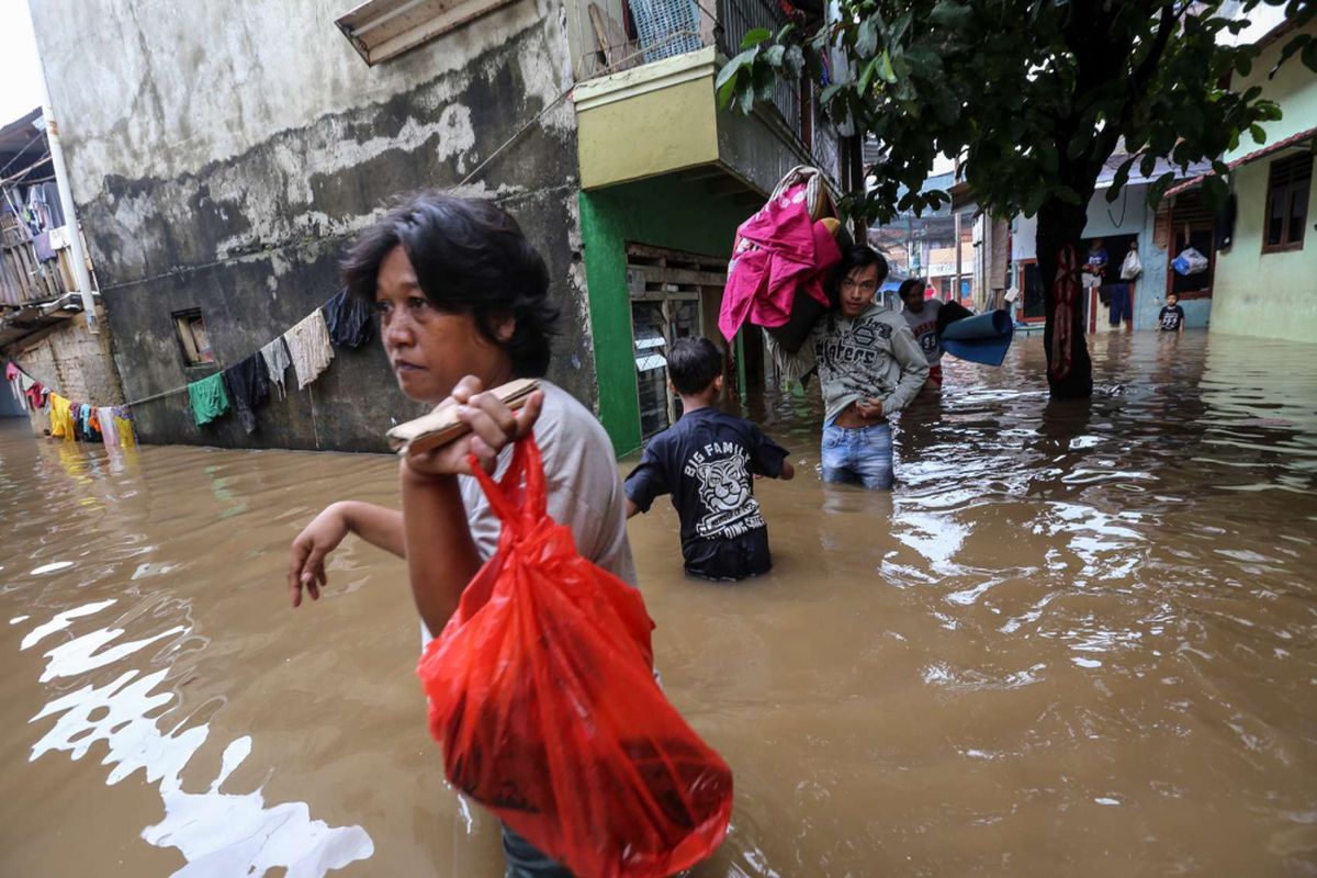 Warga mengungsi sambil membawa barang-barang berharga saat terjadi banjir di Rawajati, Pancoran, Jakarta Selatan, Senin (5/2/2018). Sebanyak 263 keluarga di Rawajati RW 007, RT 002, RT 003, RT 004, dan RT 005 dilaporkan terdampak banjir akibat luapan Sungai Ciliwung.