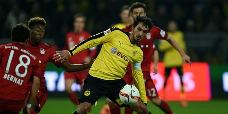 Bek Borussia Dortmund, Matt Hummels, berupaya mempertahankan bola dari para pemain Bayern Muenchen, pada laga Bundesliga di Stadion Signal Iduna Park, Sabtu (5/3/2016) waktu setempat.