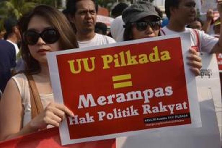 Berbagai elemen masyarakat pro demokrasi membawa poster penolakan disahkannya UU Pilkada oleh DPR yang salah satu isinya yaitu kepada daerah dipilih oleh DPRD di Jakarta, Minggu (28/9/2014).