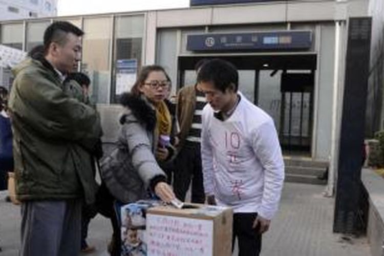 Warga Beijing menyumbangkan uang ke kotak donasi yang disediaka Xia Jun untuk mengumpulkan dana demi pengobatan putranya yang menderita leukemia.