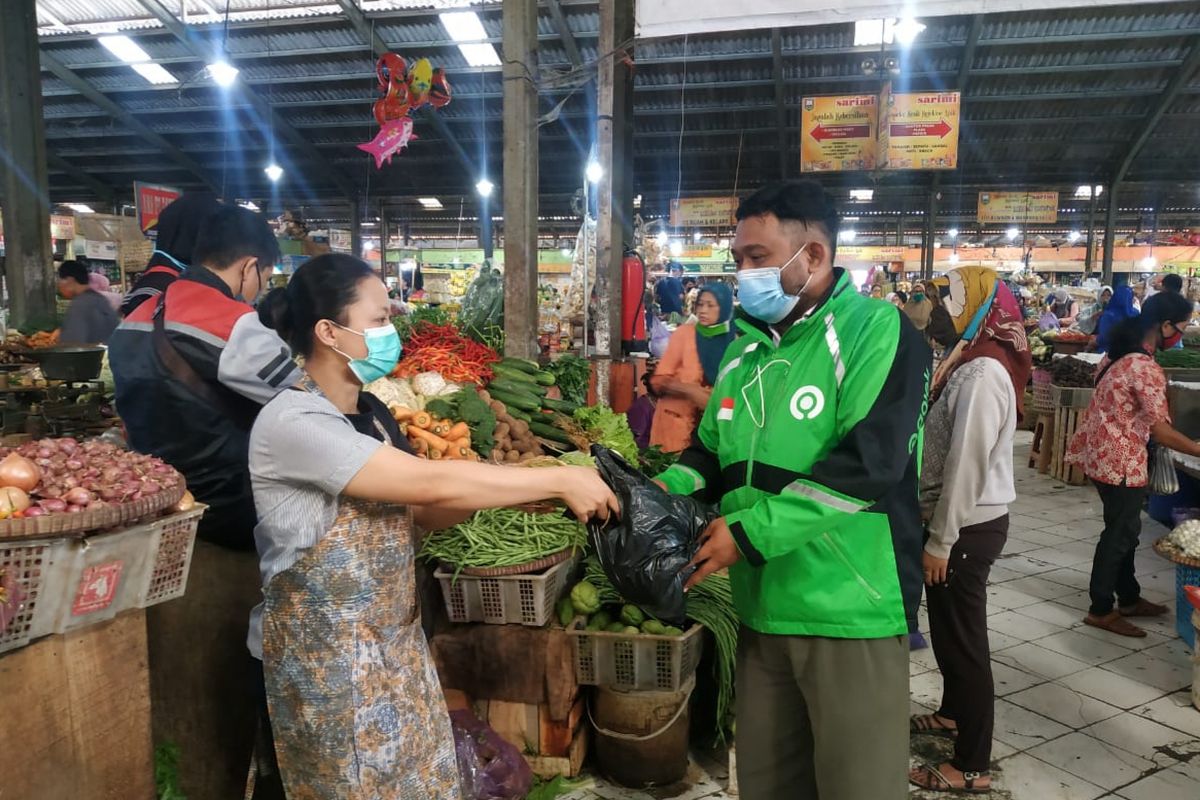 Pedagang pasar saat melayani kebutuhan bahan pokok pembeli melalui layanan daring.