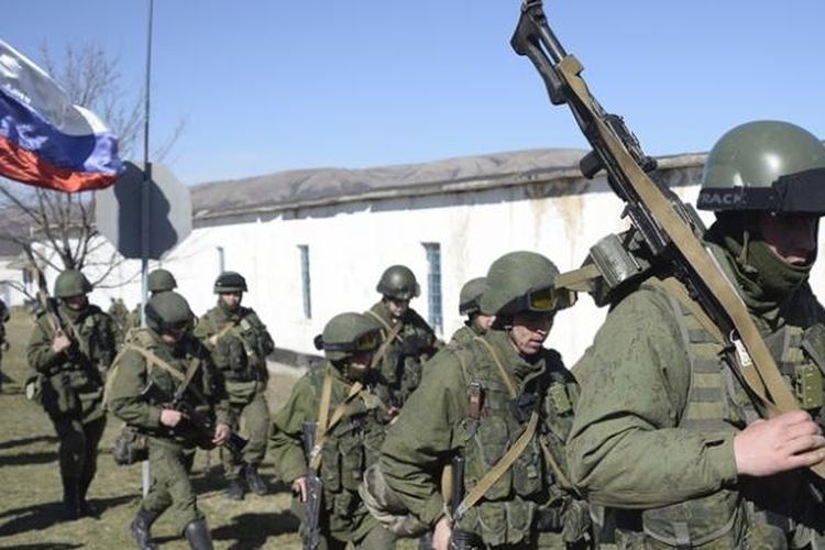 Seorang pria sambil membawa bendera Rusia menyambut rombongan pasukan bersenjata di desa Perevalne dekat ibu kota Crimea, Simferopol, Senin (3/3/2014).