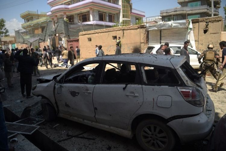 Petugas berwenang dan penduduk berada di lokasi ledakan bunuh diri di luar pusat pendaftaran pemilih pemilu legistlatif di Kabul, Afghanistan, Minggu (22/4/2018). (AFP/Shah Marai)