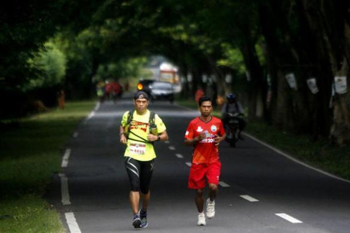 Sitor Torsina Situmorang (kiri) peserta lomba lari Trans Sumbawa dalam rangkaian Tambora Challenge 2015 lintasi Jalan Trans Sumbawa di Kecamatan Alas, Sumbawa, NTB, Rabu (8/4/2015). Lomba lari yang diikuti 8 peserta dengan 25 pelari pendamping ini dilepas dari Poto Tano dan finis di Doro Ncanga yang berjarak sekitar 320 kilometer. 