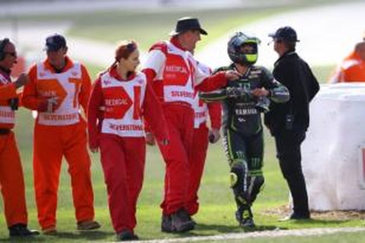 Pebalap Yamaha Tech3 asal Inggris, Cal Crutchlow, berjalan bersama para marshall setelah mengalami kecelakaan di Sirkuit Silverstone, pada sesi pemanasan GP Inggris, Minggu (1/9/2013).