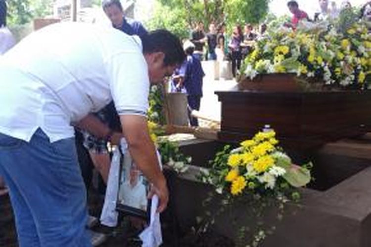 Joseph Samara meletakkan foto anaknya Hendra Gunawan sawal saat prosesi pemakaman di Sukorejo Pasuruan