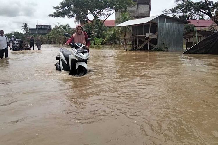 Pengendara mendorong sepeda motor di lokasi banjir Desa Rayeuk Kuta, Kecamatan Tanah Pasir, Kabupaten Aceh Utara, Rabu (21/12/2022)
