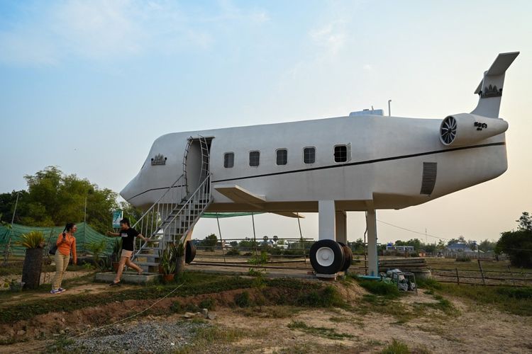 Foto yang diambil pada 12 Maret 2023 ini memperlihatkan pengunjung sedang berjalan-jalan di sekitar rumah berbentuk pesawat terbang di Siem Reap, Kamboja. Rumah tersebut dimiliki dan dibangun oleh Chrach Peou (43)