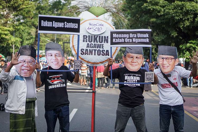 Warga dengan mengenakan topeng Capres Cawapres, Joko Widodo-Maruf Amin dan Prabowo Subianto-Sandiaga Uno melakukan aksi pesan damai di Solo, Jawa Tengah, Minggu (21/4/2019). Aksi tersebut sebagai pesan harapan damai setelah berlangsungnya Pilpres 2019 dengan mengajak masyarakat untuk menunggu hasil rekapitulasi dan menghormati keputusan dari Komisi Pemilihan Umum (KPU).