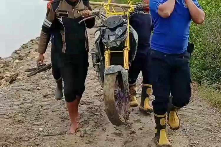 Petugas Damkar Sumenep menandu motor melewati jalan berlumpur dan licin. 
