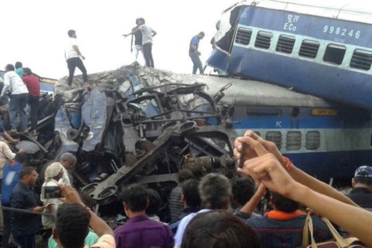 Polisi dan sukarelawan mencari korban selamat di bawah bangkai kereta yang tergelincir keluar dari jalurnya di India utara, Sabtu (19/8/2018). Laporan menyebutkan, 23 orang tewas.