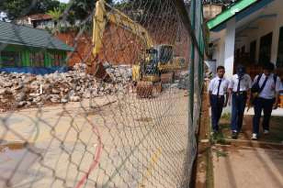 Aktivitas alat berat saat membersihkan material longsor yang merusak ruang kelas di SMP Negeri 19 Tangerang Selatan, Ciater Serpong, Kota Tangerang Selatan, Senin (9/1/2017). Sebagian gedung sekolah tersebut rusak karena tertimpa longsor setelah turap tebing di belakang sekolah jebol pada 5 Januari 2017 lalu.