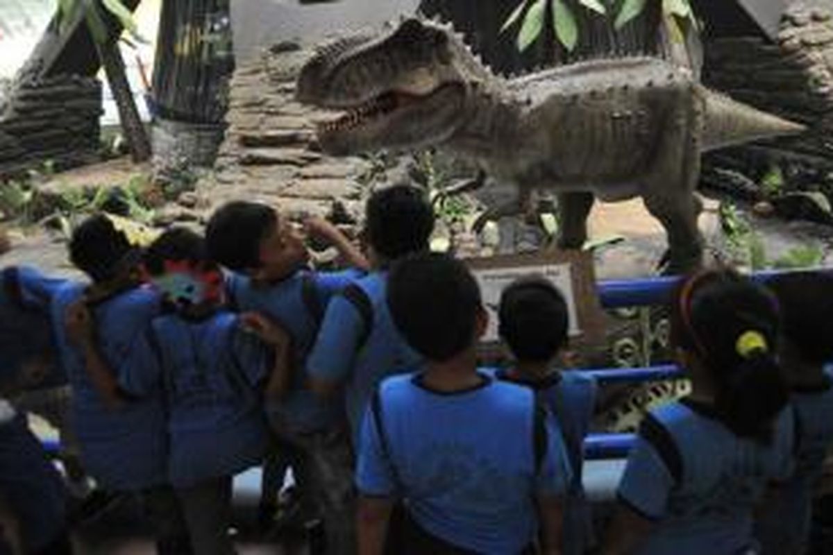 Pelajar melihat replika binatang purba Tyrannosaurus rex yang dipajang di Museum Pusat Peraga Ilmu Pengetahuan dan Teknologi di Taman Mini Indonesia Indah di Jakarta, Kamis (20/6/2013). Wahana binatang purba ini dibuat dalam ukuran aslinya dan dapat bergerak serta mengeluarkan suara sehingga mampu mengajak pengunjung belajar sains secara nyata.