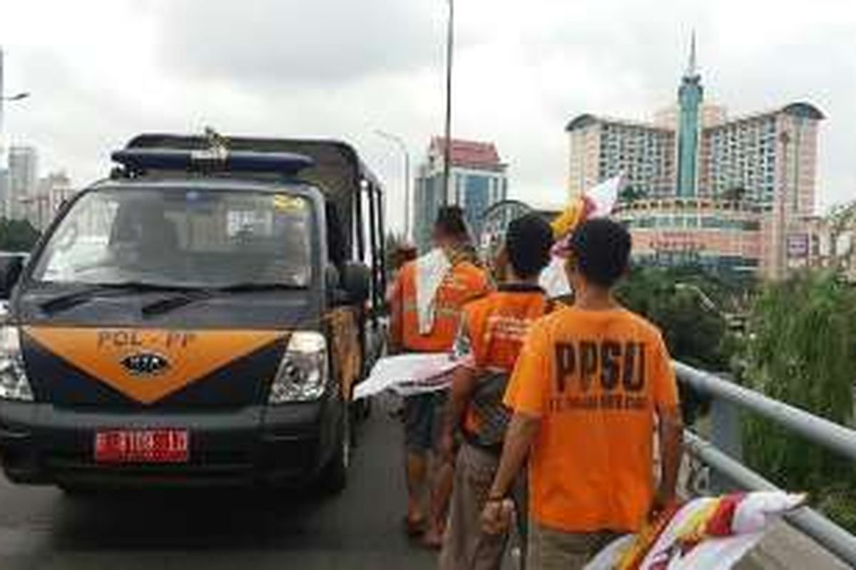 Petugas PPSU Kelurahan Tanjung Duren Utara seusai mencabuti bendera partau politik Gerindra yang terpasang di sepanjang jembatan Grogol, Jakarta, Rabu (10/2/2016).