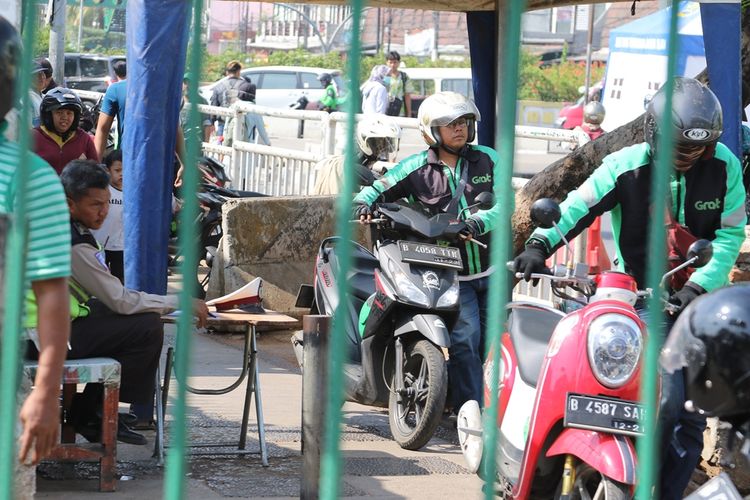 Pengendara motor berjalan menuntun motornya ketika melawan arah melewati polisi yang berjaga di dekat Stasiun Pasar Minggu, Jakarta Selatan, Selasa (19/11/2019). Hal itu dilakukan agar tidak kena tilang.