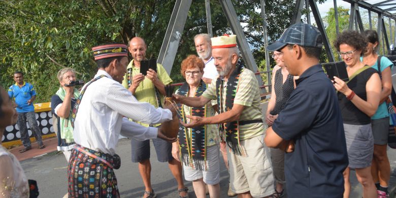 Ketua rombongan turis Italia dan Jerman menerima Moke Kepok Sundung di Jembatan Waemokel, Manggarai Timur, NTT, Rabu (15/8/2018).