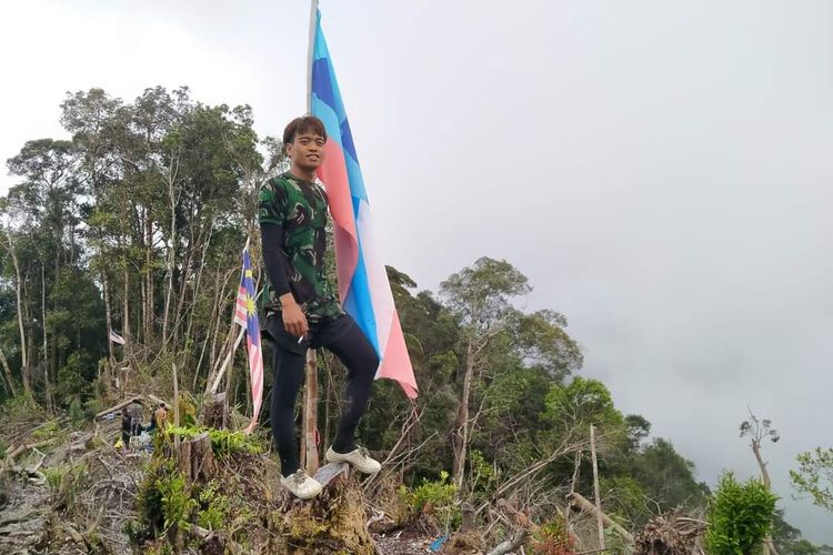 Warga Lumbis Hulu Nunukan Kaltara berpose dengan latar bendera Malaysia yang mereka temukan di perbukitan tengah hutan saat berburu. Warga perbatasan mempertanyakan keberadaan bendera negara tetangga yang tertancap di wilayah NKRI