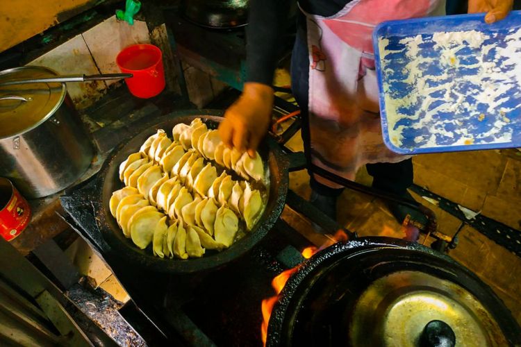 Pegawai Kuo Tieh Shandong 68 di bilangan Pancoran Jakarta Barat sedang menyiapkan adonan kuo tieh yang akan dipanggang di wajan khusus berbahan baja. Kuo tieh dipanggang menggunakan api besar.