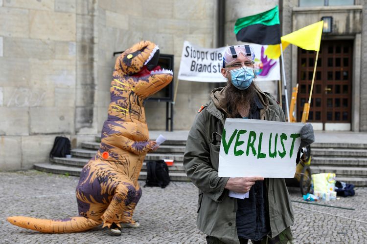 Seorang demonstran mengenakan masker dan kacamata pelindung sambil membawa plakat bertuliskan KERUGIAN, dalam demonstrasi Hari Buruh Internasional di Berlin, Jerman, 1 Mei 2020.