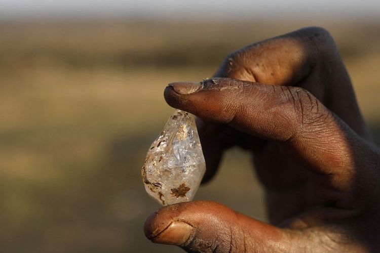 Seorang anak laki-laki memegang apa yang dia yakini sebagai berlian setelah penemuan batu tak dikenal di desa KwaHlathi dekat Ladysmith, Afrika Selatan, pada 15 Juni 2021.