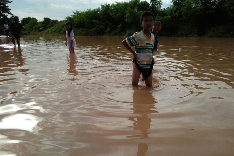 Anak-anak di Perum BMI,  Desa Dwuhan Tengah, Kecamatan Cikampek, Karawang,  Kamis (4/1/2018) melintas di area yang terendam banjir. Perumahan ini terendam sejak Rabu (3/1/2018) sore. 