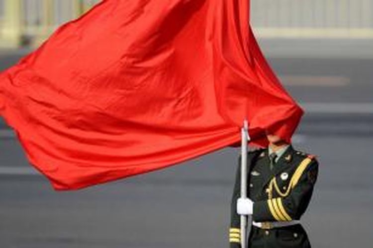 Angin menghembus bendera merah ke wajah penjaga China saat ia berdiri sebelum Presiden Sri Lanka Mahinda Rajapaksa dan Presiden China Xi Jinping menginspeksi pasukan dalam upacara penyambutan di luar Balai Besar Rakyat di Beijing, 28 Mei 2013. Mahinda Rajapaksa melakukan kunjungan dua hari ke China.