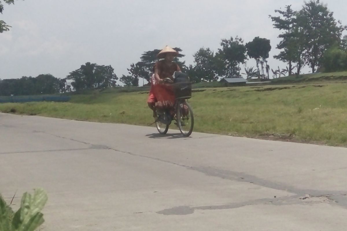 Seorang ibu memboncengkan anaknya saat melintasi ruas jalan Karanganyar - Dempet,  Kabupaten Demak,  Jateng,  yang dibangun Pemkab Demak dengan cor beton,  Sabtu (25/3/2017)