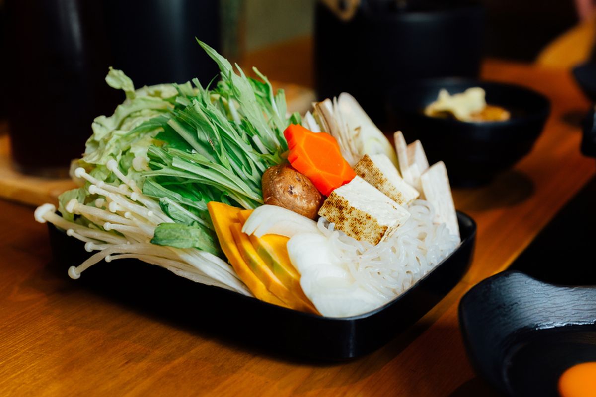 Ilustrasi sukiyaki sayuran, terdiri dari sawi, pok coy, wortel, shiitake, enokitake, tahu, labu, daun bawang, dan mi. 