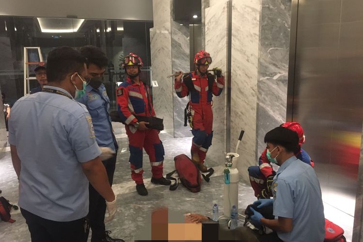 Sejumlah petugas gabungan tengah membantu seorang korban yang berhasil diselamatkan usai terjebak di dalam lift Gedung Pakuwon Tower, Jakarta Selatan, Senin (8/5/2023) malam. 