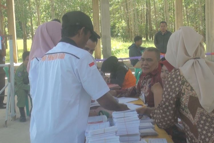 Ferdianto, anggota KPPS Patih Galung (kemeja putih) menyerahkan kertas suara untuk pemilihan presiden dan wakil presiden yang diproleh dari TPS sekitar ke petugas di TPS agar bisa digunakan oleh warga 