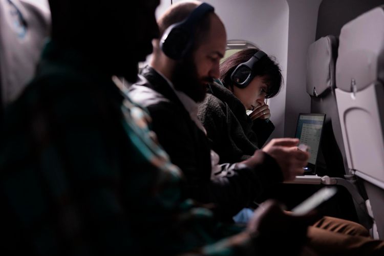 Ilustrasi penumpang pesawat menggunakan headphone

