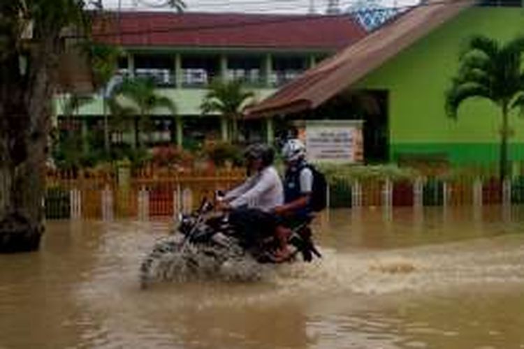 Warga melintas di depan SDN 2 Lhoksukon, Aceh Utara yang terendam banjir, Selasa (9/2/2016)