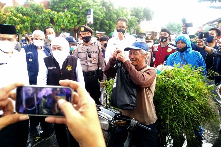 Gubernur Jawa Timur Khofifah Indar Parawansa memberikan paket sembako kepada seorang pencari rumput yang sedang melintas di lokasi yang dikunjunginya di Kecamatan Kademangan, Kabupaten Blitar, Rabu (16/3/2022)