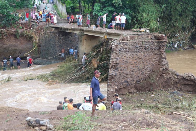 Warga Desa Banjaragung, Kecamatan Bareng, Kabupaten Jombang, Jawa Timur, membersihkan sampah yang tersangkut di kolong jembatan Sungai Pakel, Selasa (2/2/2021). Jembatan terputus akibat banjir bandang, pada Senin malam.
