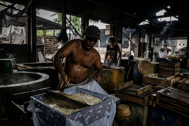 Seorang pekerja sedang memproses kedelai untuk dijadikan tahu. Sejumlah pabrik tahu di Tropodo, Indonesia, menggunakan plastik sebagai bahan bakar.