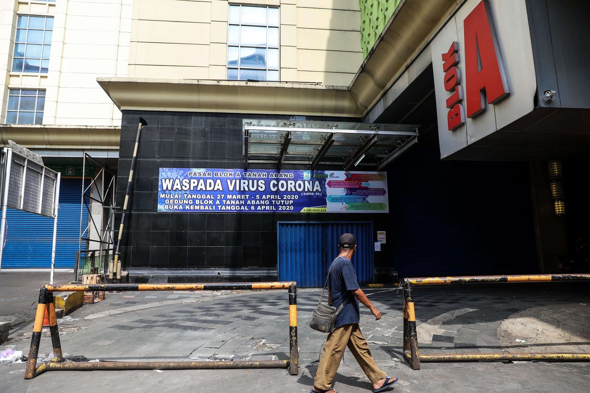 Seorang warga melintas di samping poster yang bertuliskan penuputan pasar jaya sementara di Tanah Abang, Jakarta Pusat, Sabtu (28/3/2020). Perumda Pasar Jaya memutuskan untuk menutup sementara Blok A, Blok B, dan Blok F dan hanya membuka Blok G, itu pun dibatasi hanya pedagang bahan pangan saja yang diperbolehkan berjualan. Penutupan sementara dilakukan untuk mencegah penyebaran virus corona tipe 2 (SARS-CoV-2) yang menyebabkan covid-19.